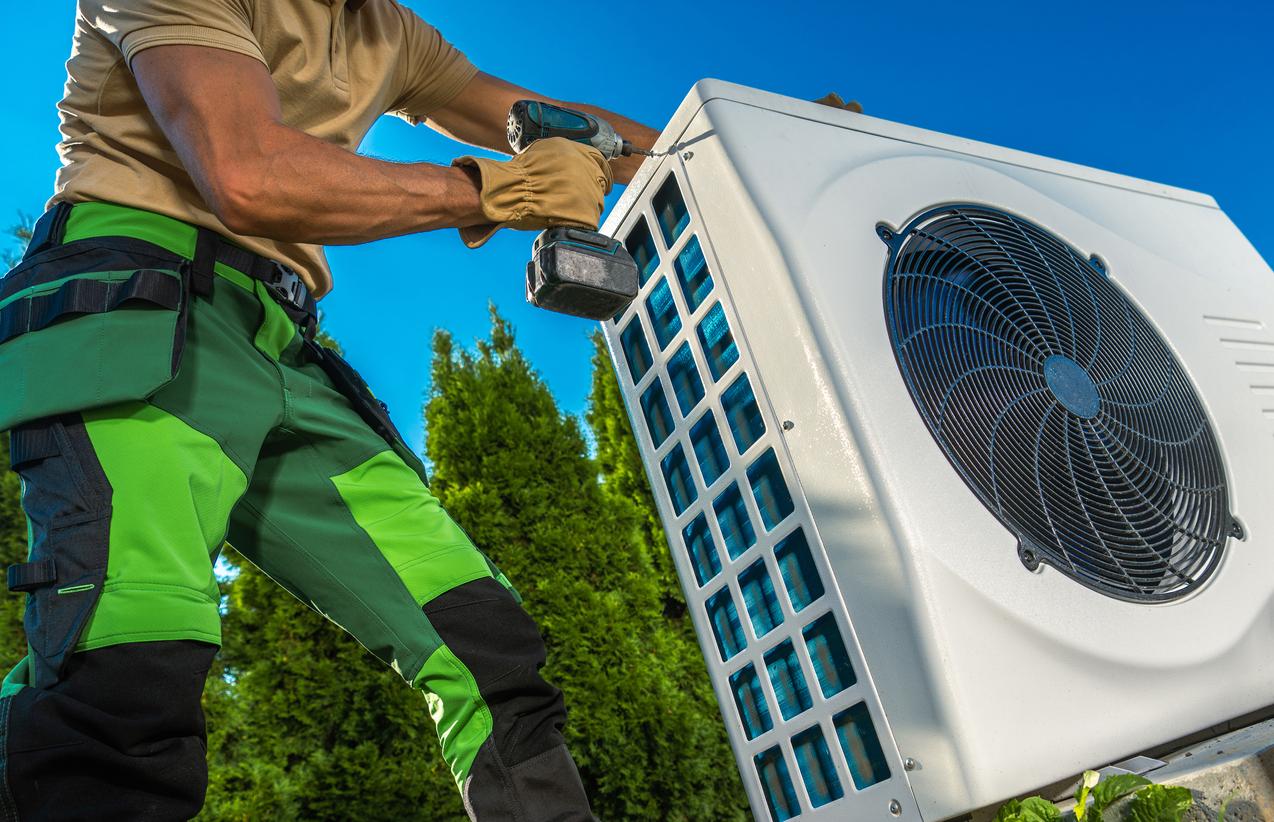 HVAC technicians installing a large heat pump outside.