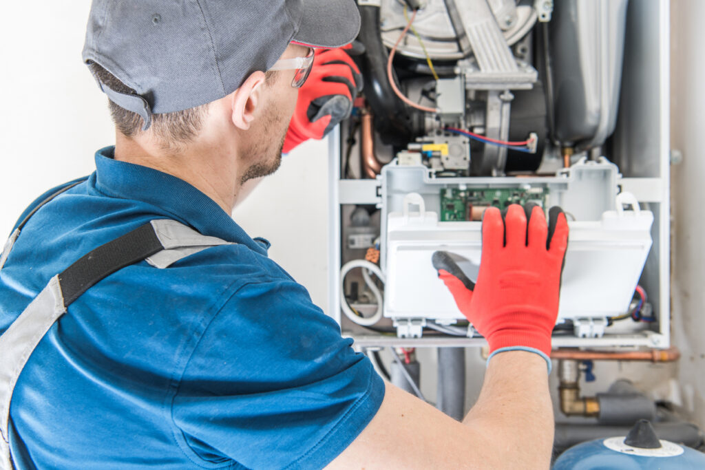 An HVAC technician repairing a gas furnace.