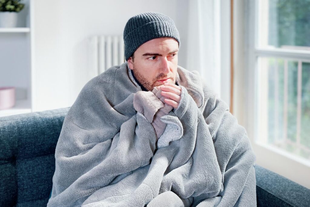 A man sitting at home in the cold.