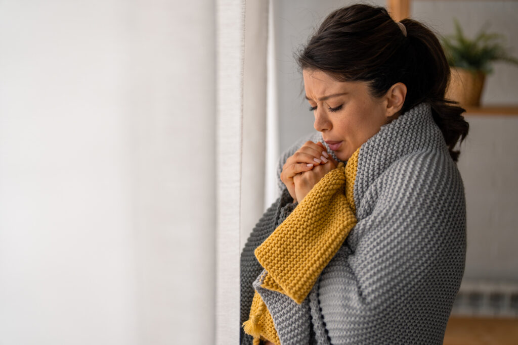 Woman breathing on her hands to keep them warm.