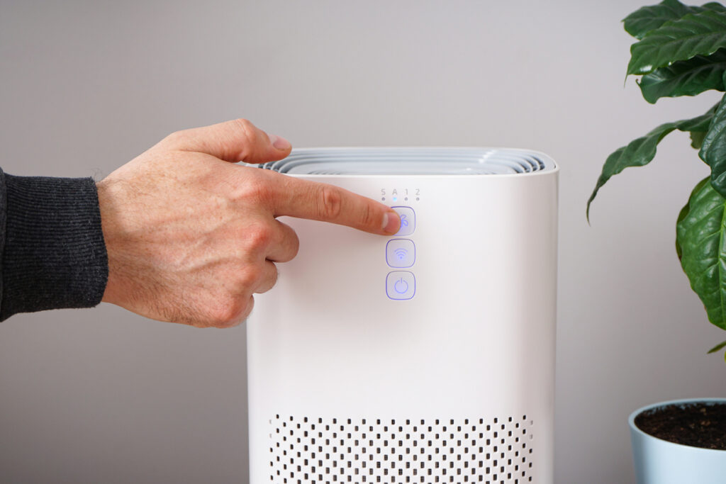 Man with modern air purifier in his room. 