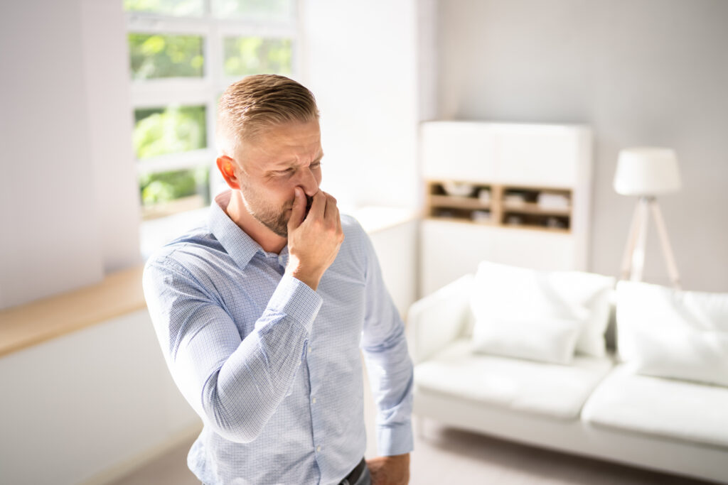 A man pinches his nose after smelling something foul from the air conditioner. 